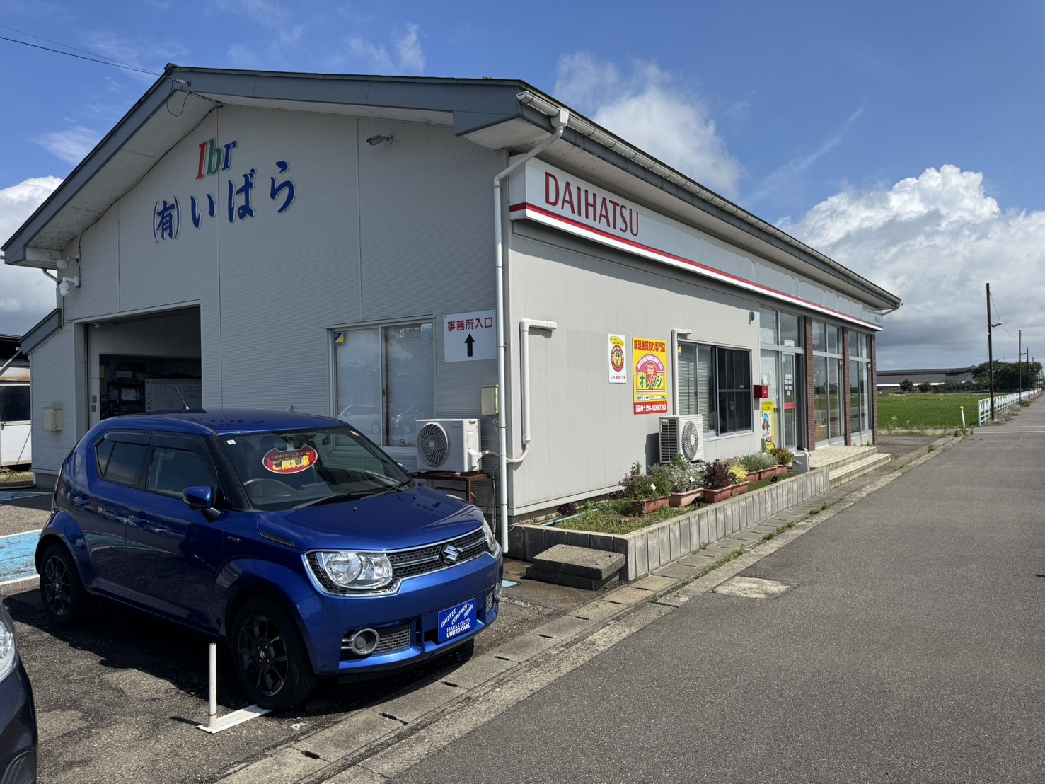 「(有)いばら」の看板の下に停めた青い車