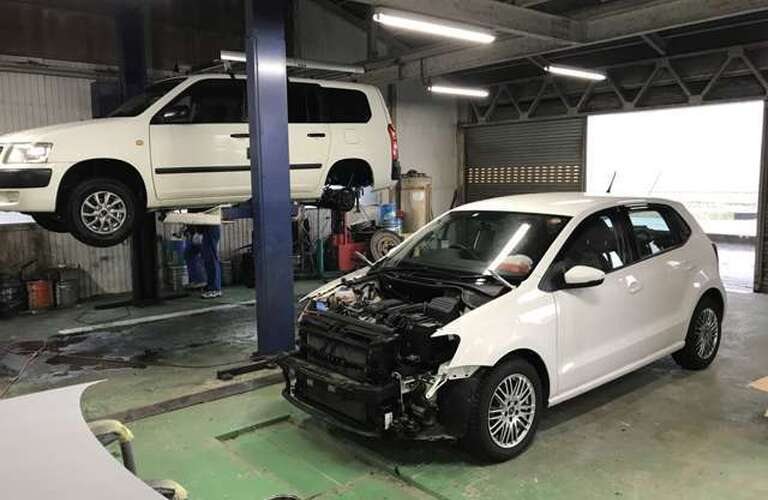 バンパーを外した車とリフトに上げた車がある工場